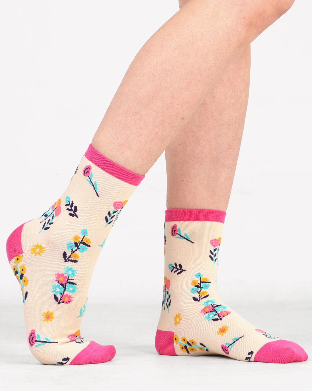 Floral-patterned socks with pink accents worn by a person on a white background