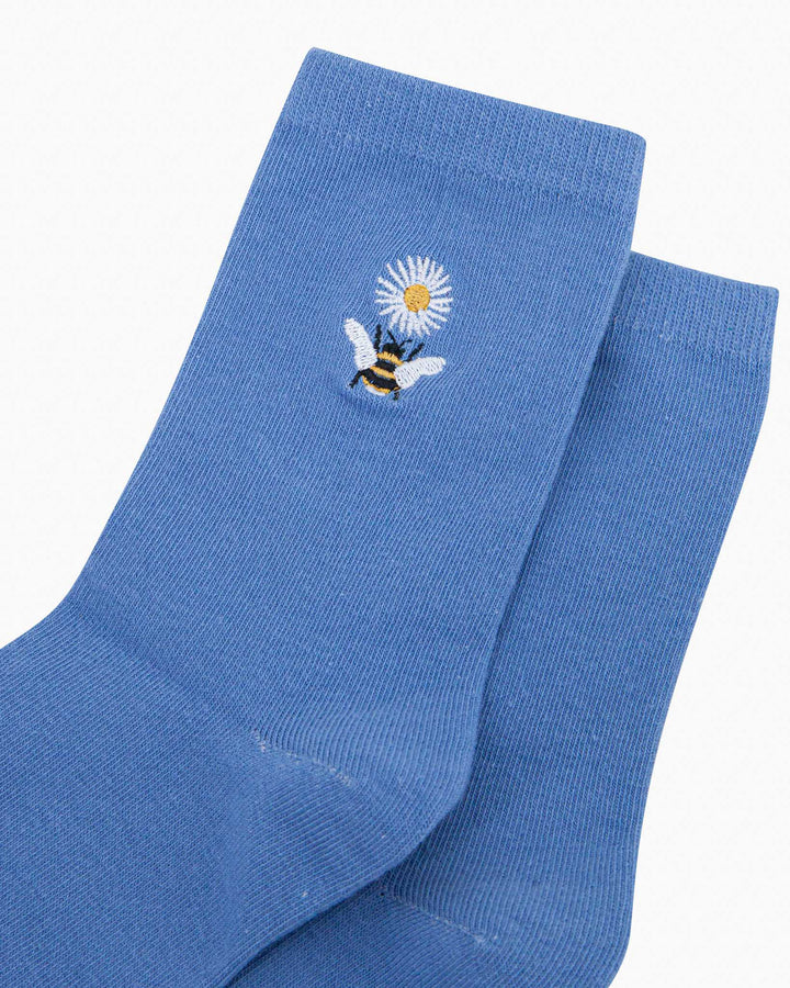 Blue socks with a bee and flower design on a white background