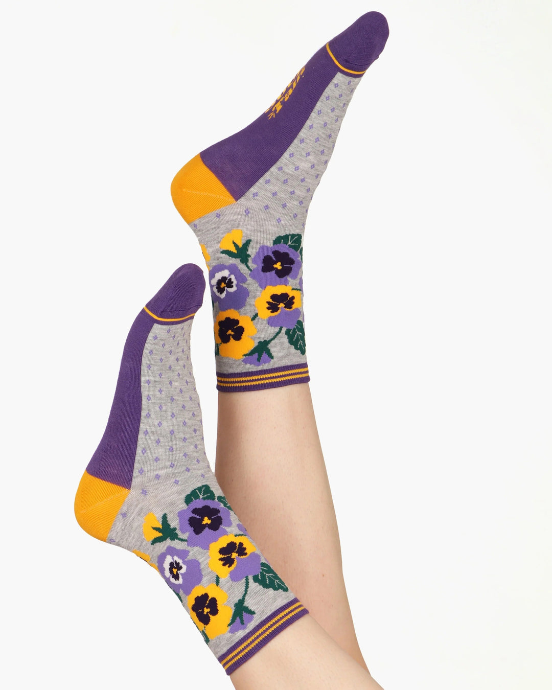 Gray socks with purple and yellow floral patterns worn by a person on a white background