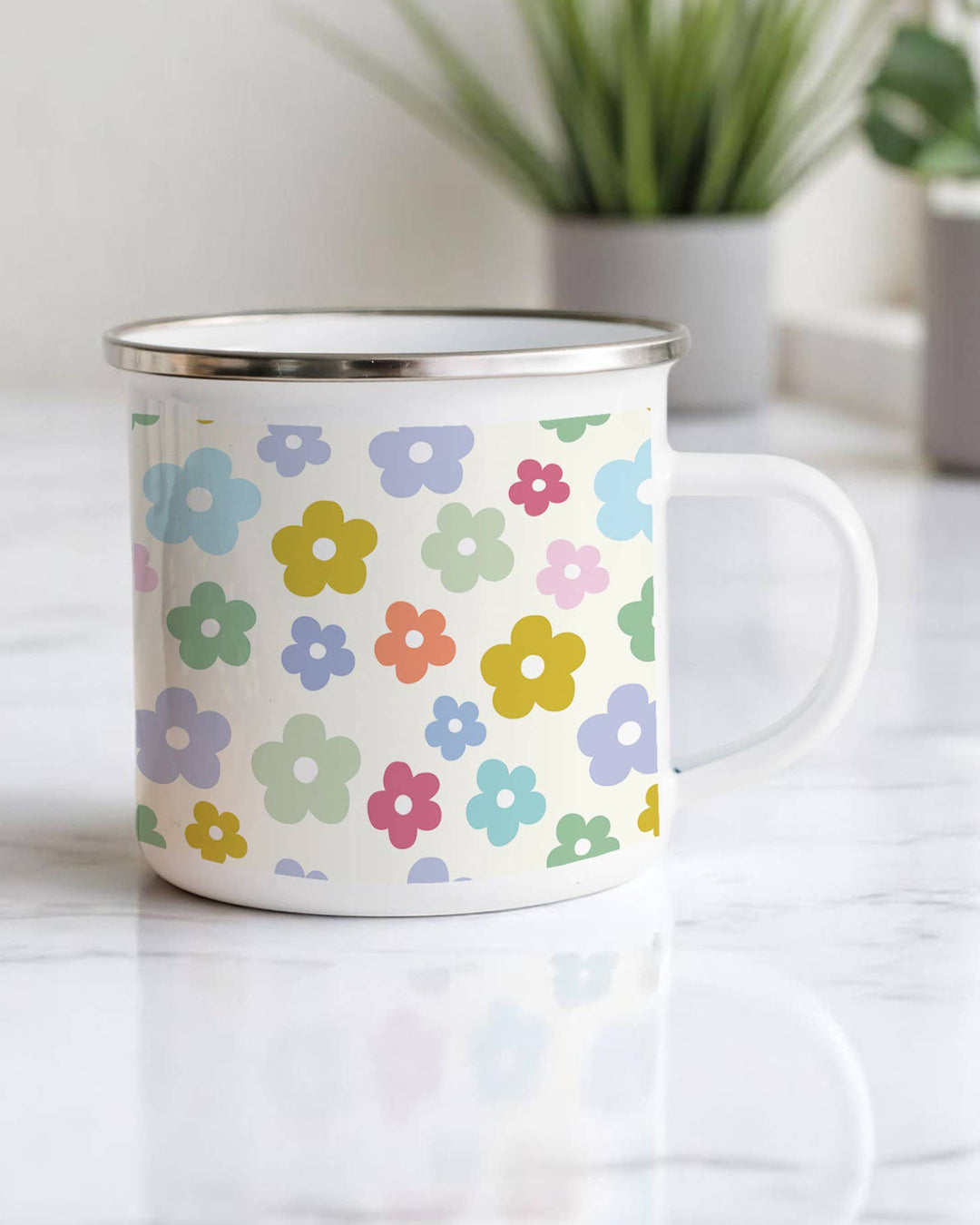 White mug with colorful floral pattern on a white surface with plants in the background