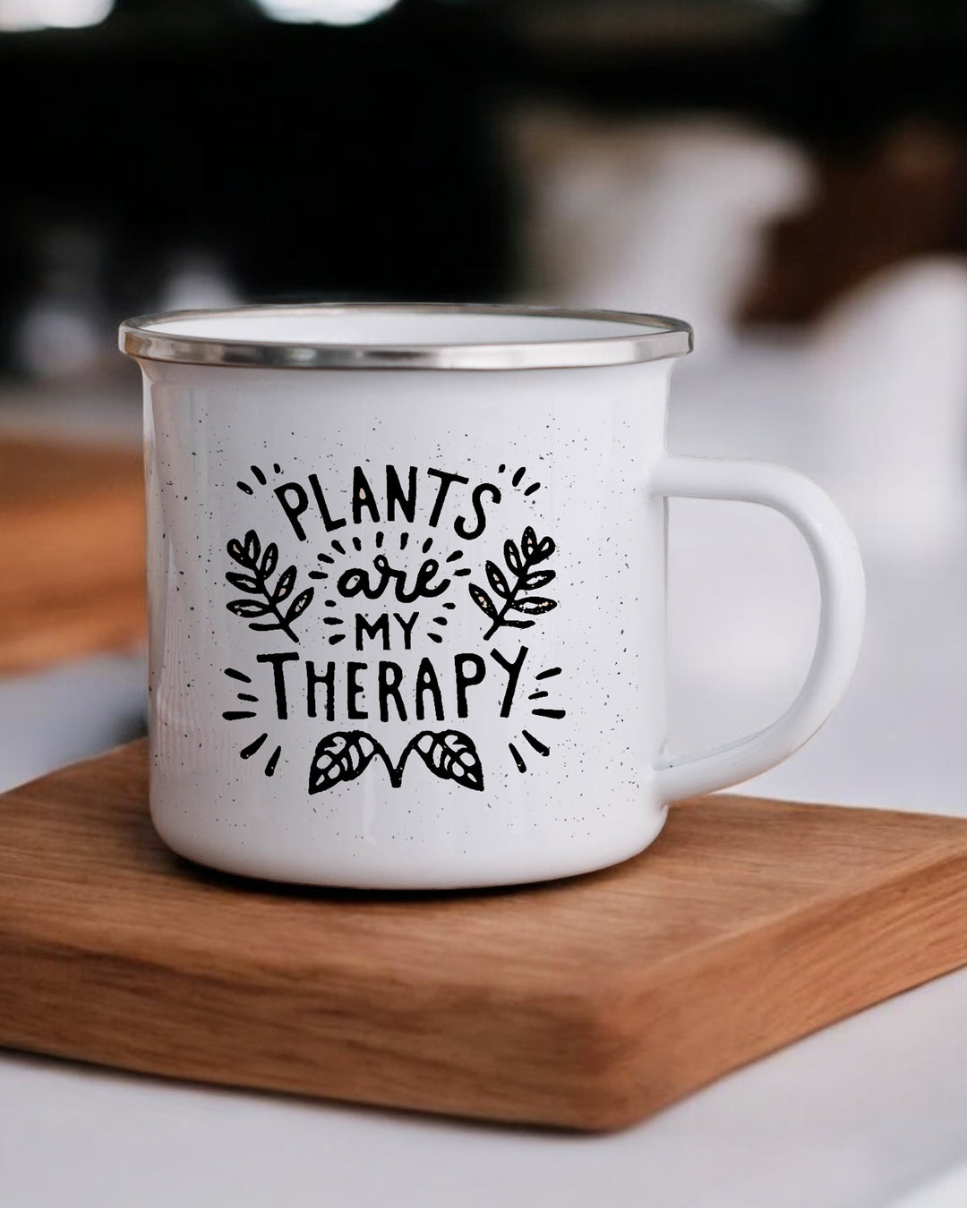 White mug with 'Plants are my therapy' text on a wooden coaster.