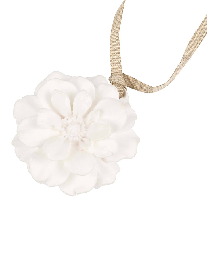 White flower-shaped bath bomb with a beige ribbon on a white background