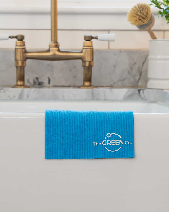 Blue cleaning mat with 'The GREEN Co.' logo on a bathtub