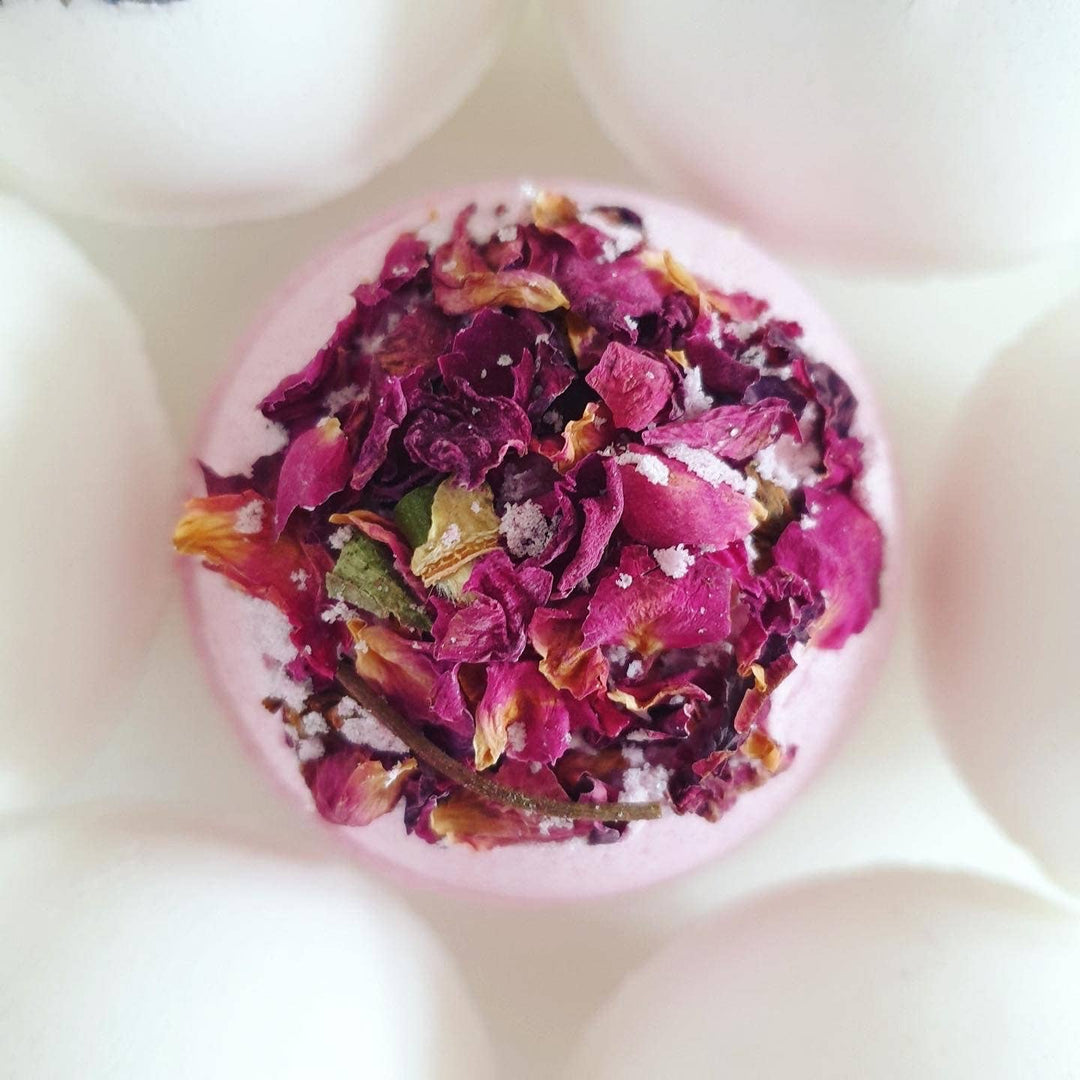 Bath bomb with pink and purple dried flowers and salt crystals on a white background