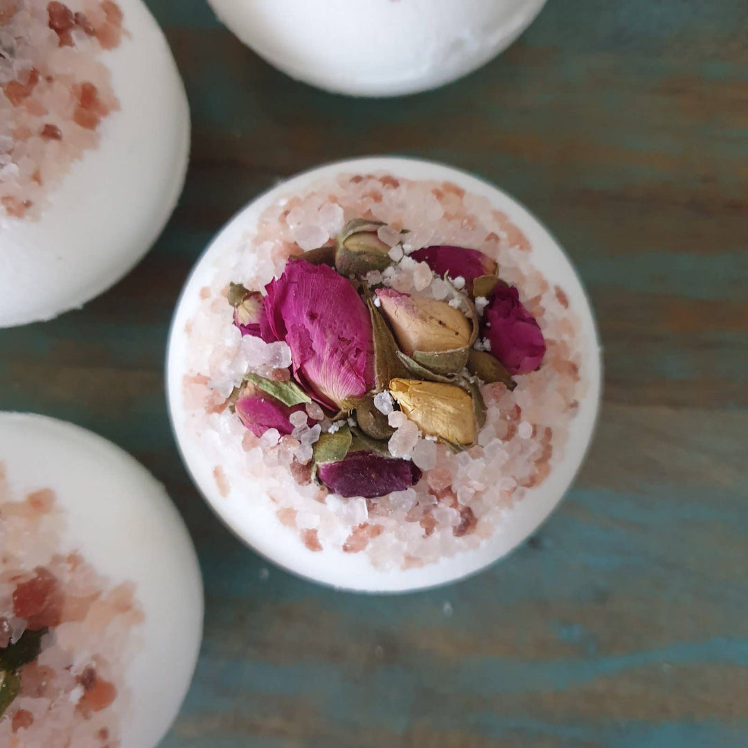 Bath bombs with pink and green bath salts on a textured surface