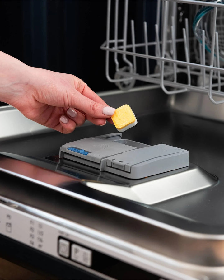 Person using a dishwasher tablet with a dishwasher in the background