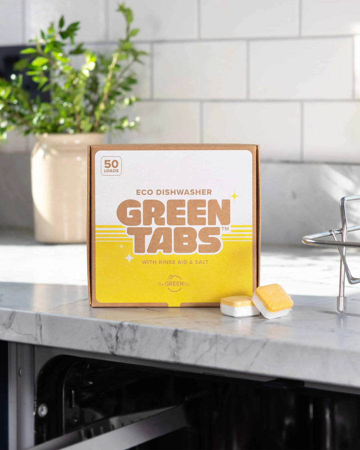 Box of Green Tabs eco dishwasher tablets on a kitchen counter with a plant in the background.