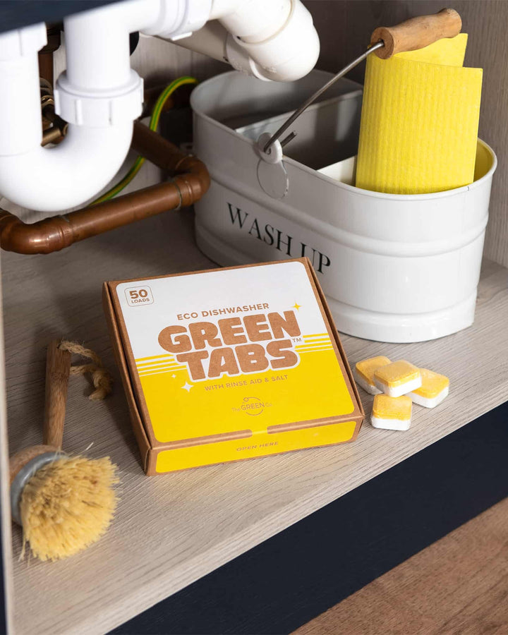 Box of Green Tabs eco dishwasher tablets with yellow tabs on a kitchen counter.