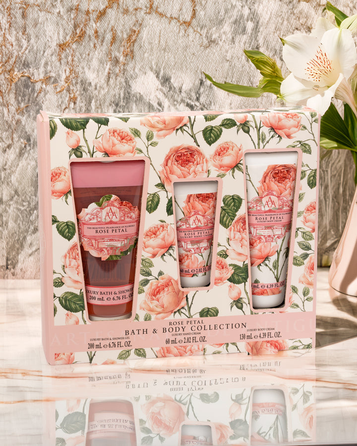 Rose Petal bath and body collection set with floral packaging on a marble surface.