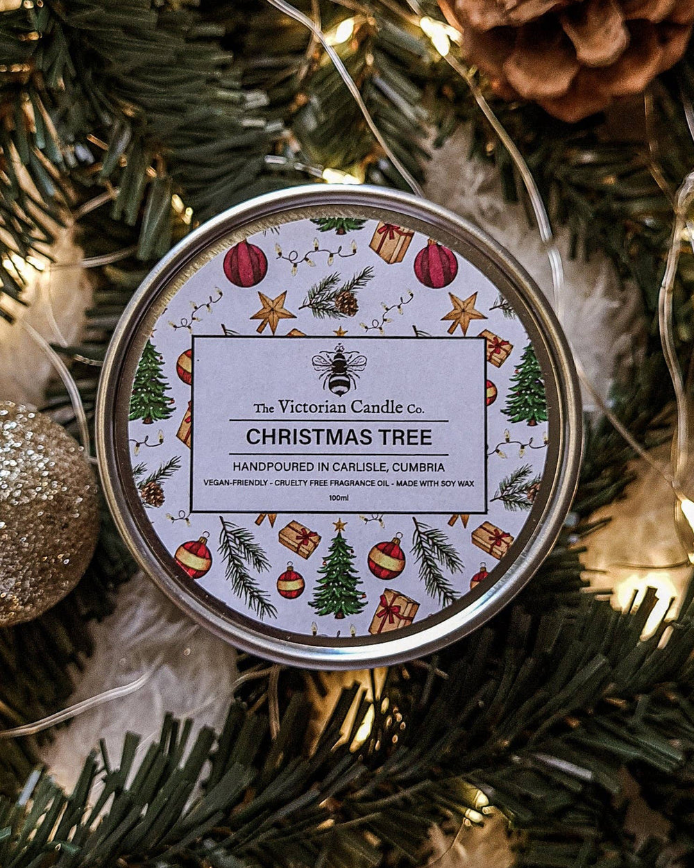Candle tin labeled 'Christmas Tree' by The Victorian Candle Co. on a festive background.