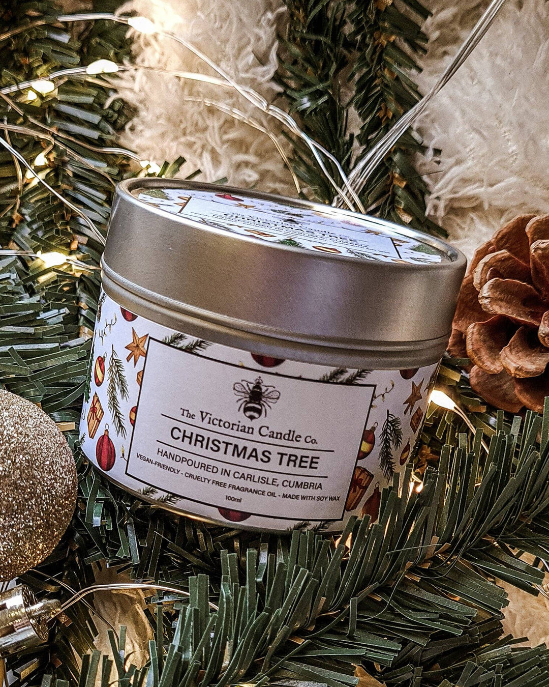Candle labeled 'Christmas Tree' from The Victorian Candle Co. on a decorative background with greenery and lights.