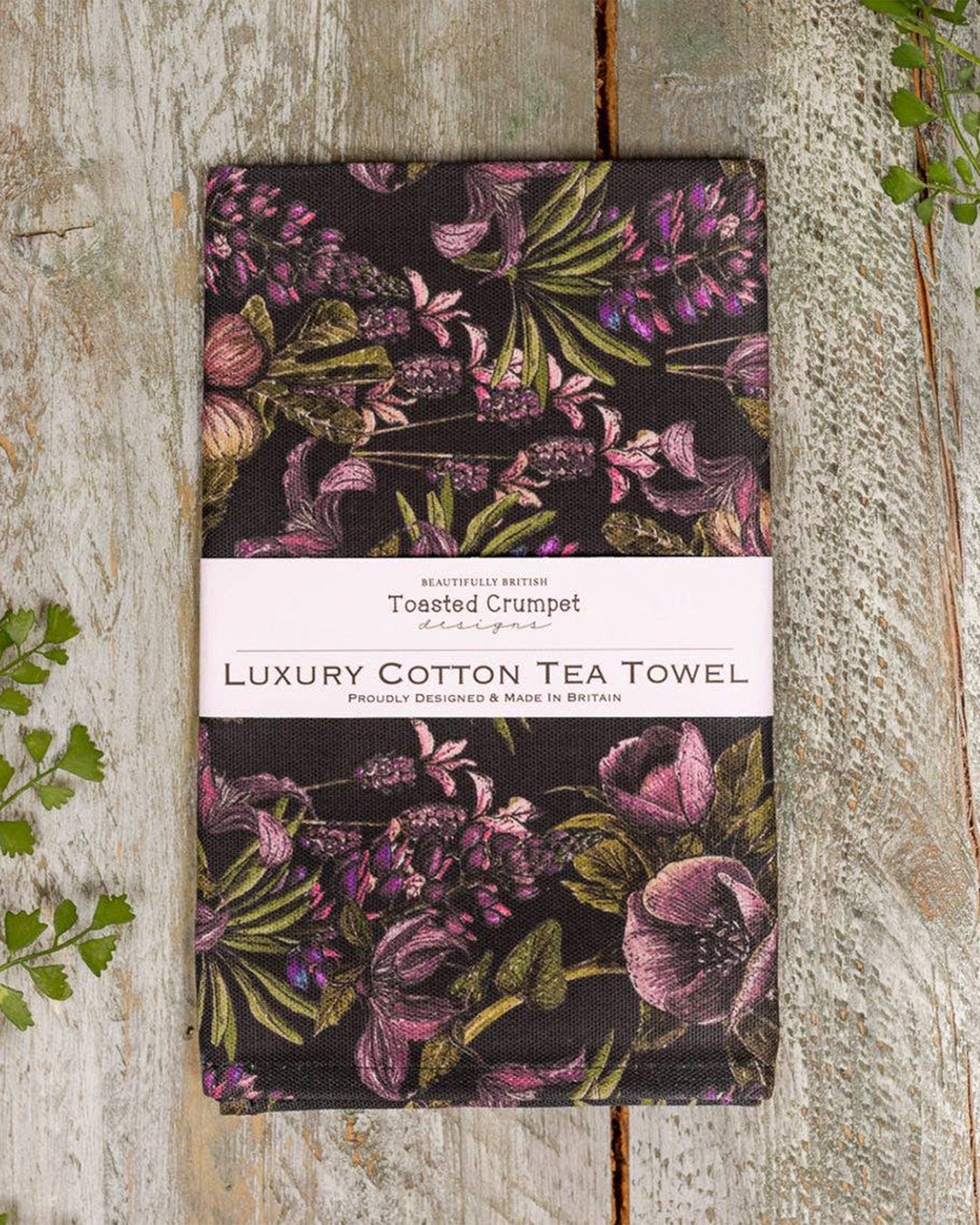 Floral patterned tea towel packaging on a wooden surface