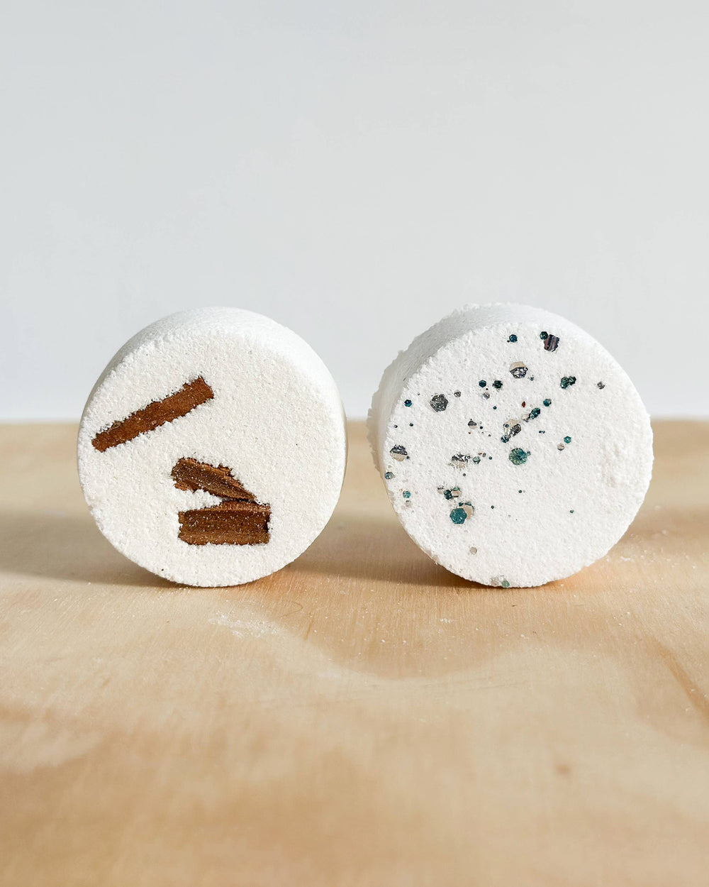 Two round bath bombs on a wooden surface with a light background