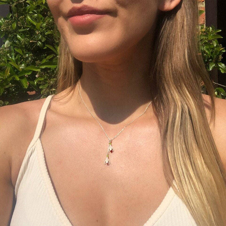 Close-up of a person wearing a necklace with a pendant outdoors