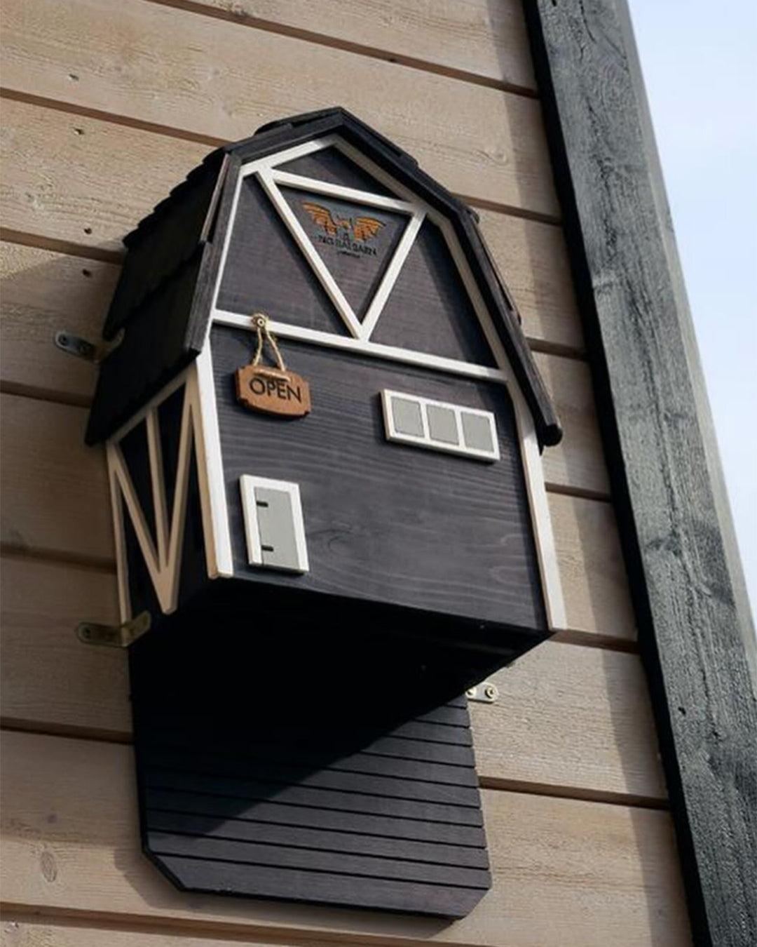 Decorative black bat box with wooden accents on a wooden wall.