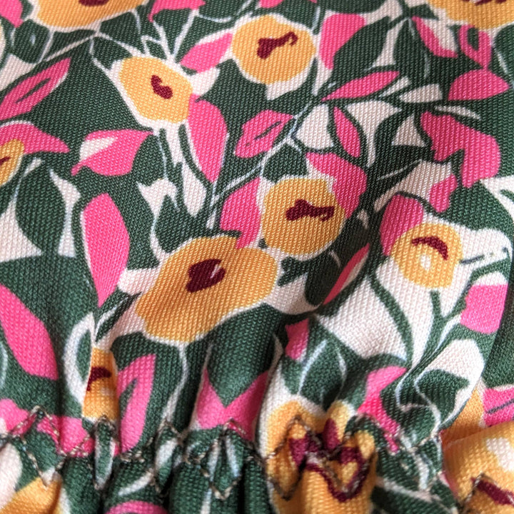 Close-up of floral fabric with pink, yellow, and green colors.