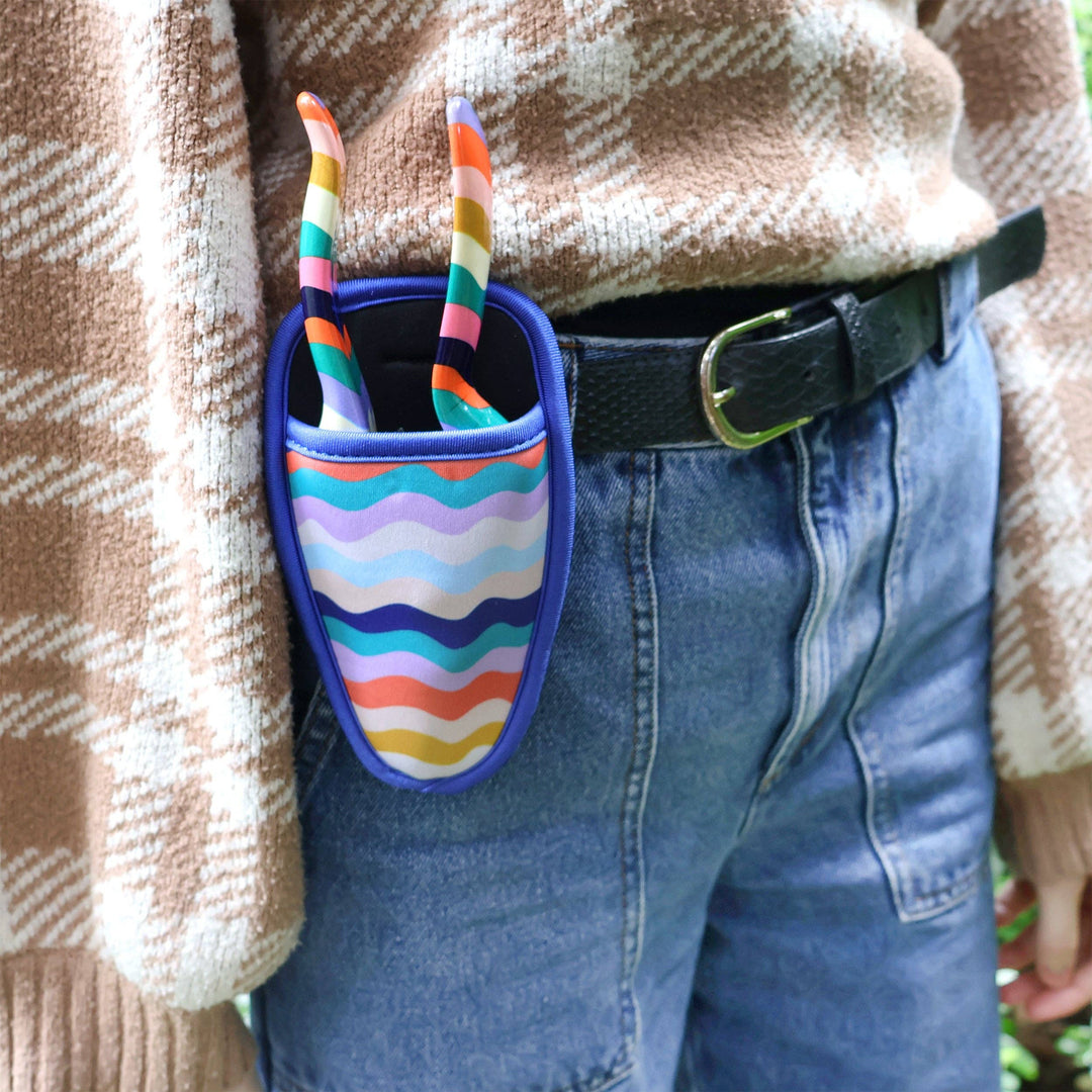 Colorful striped shoe bag attached to a person's waist with a plaid shirt and jeans.