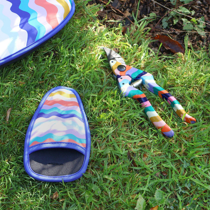 Colorful garden shears and slipper on grass