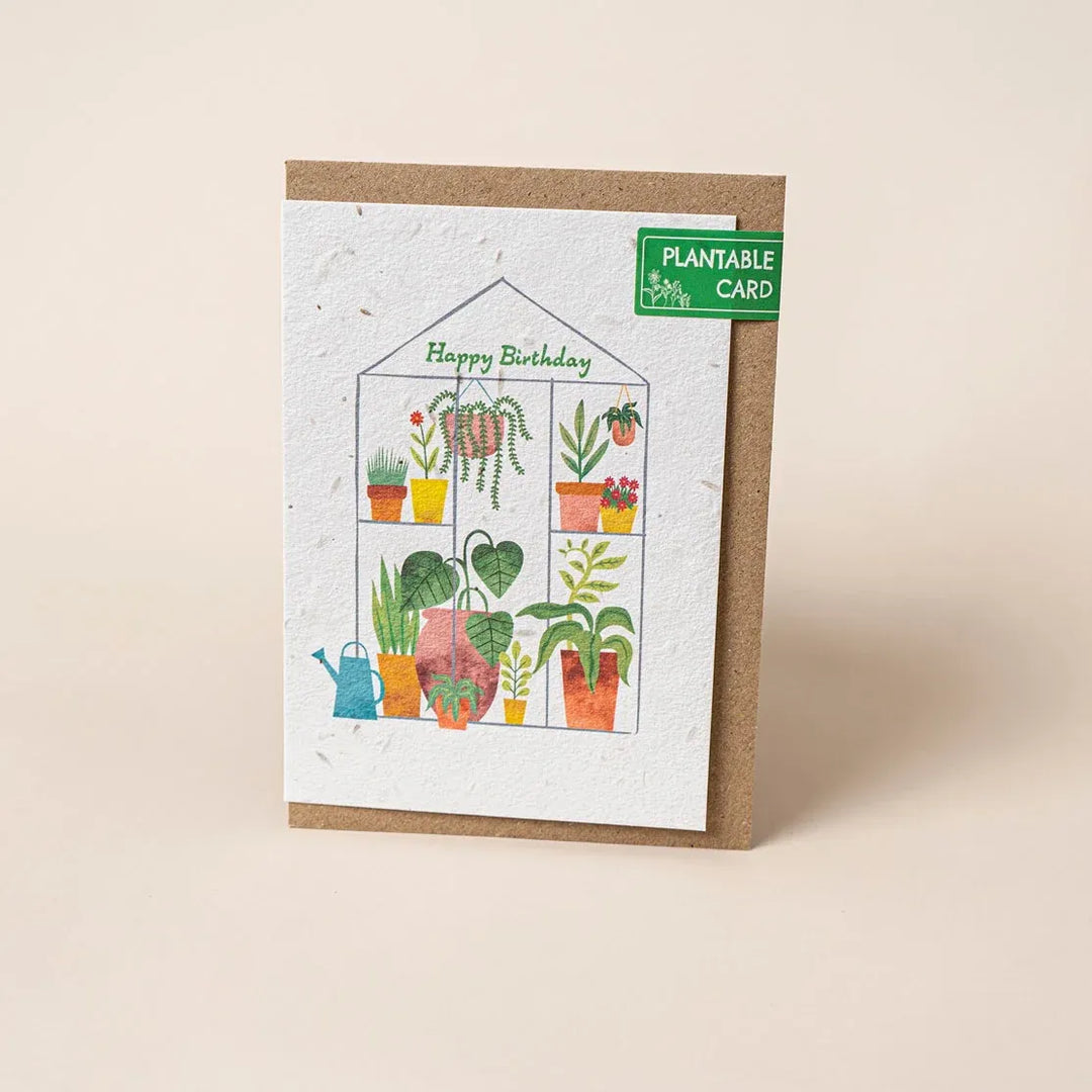 Plantable birthday card with illustrations of plants and a greenhouse on a beige background.