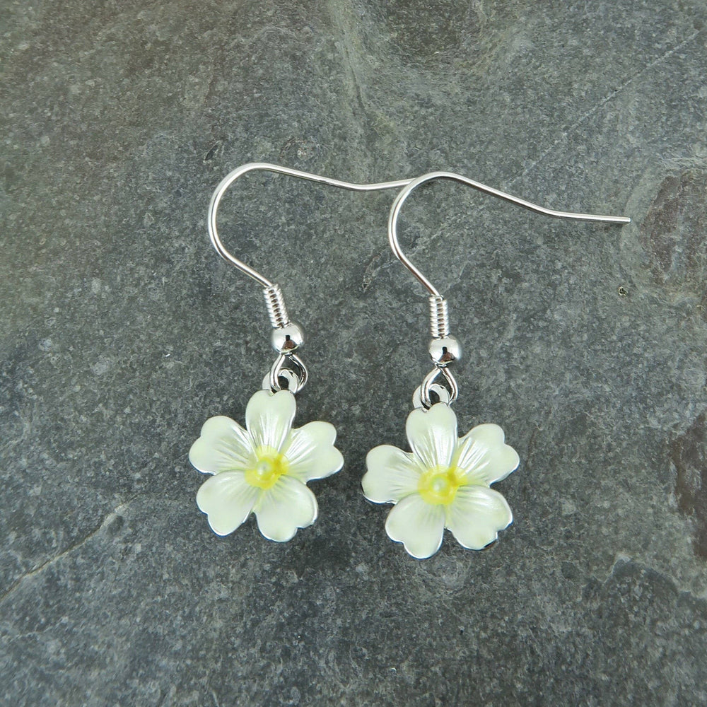 Flower-shaped earrings on a gray stone surface