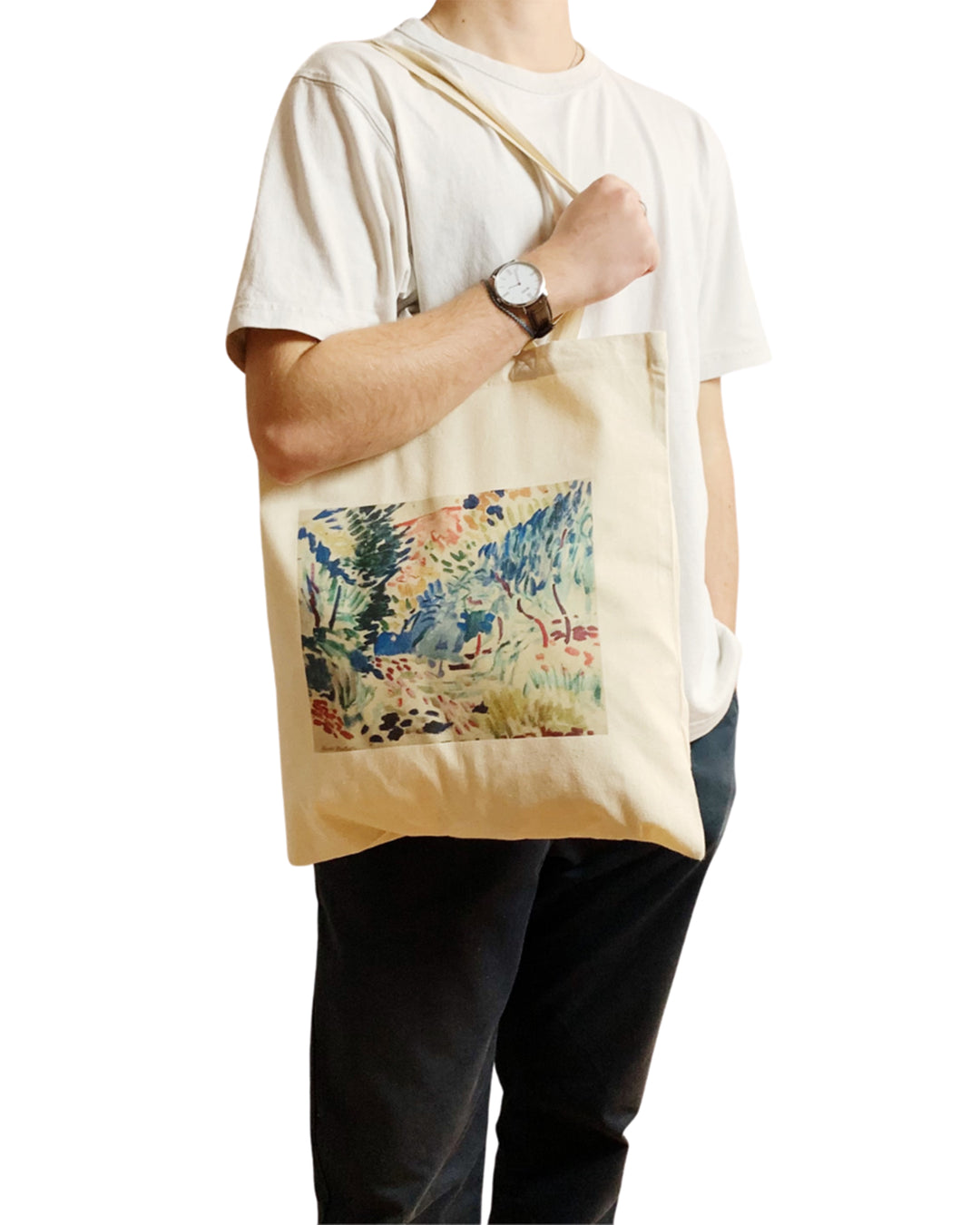 Person holding a beige tote bag with a colorful floral design on a white background