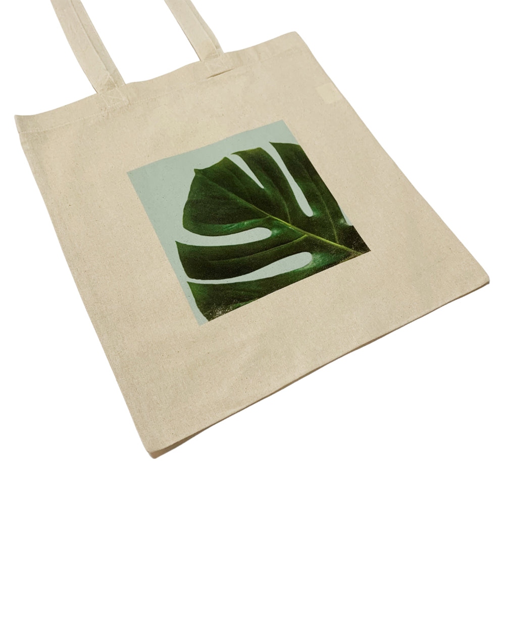Beige tote bag with a green leaf design on a white background