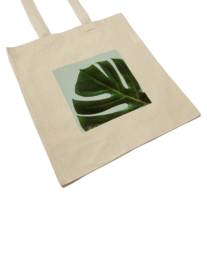 Beige tote bag with a green leaf design on a white background