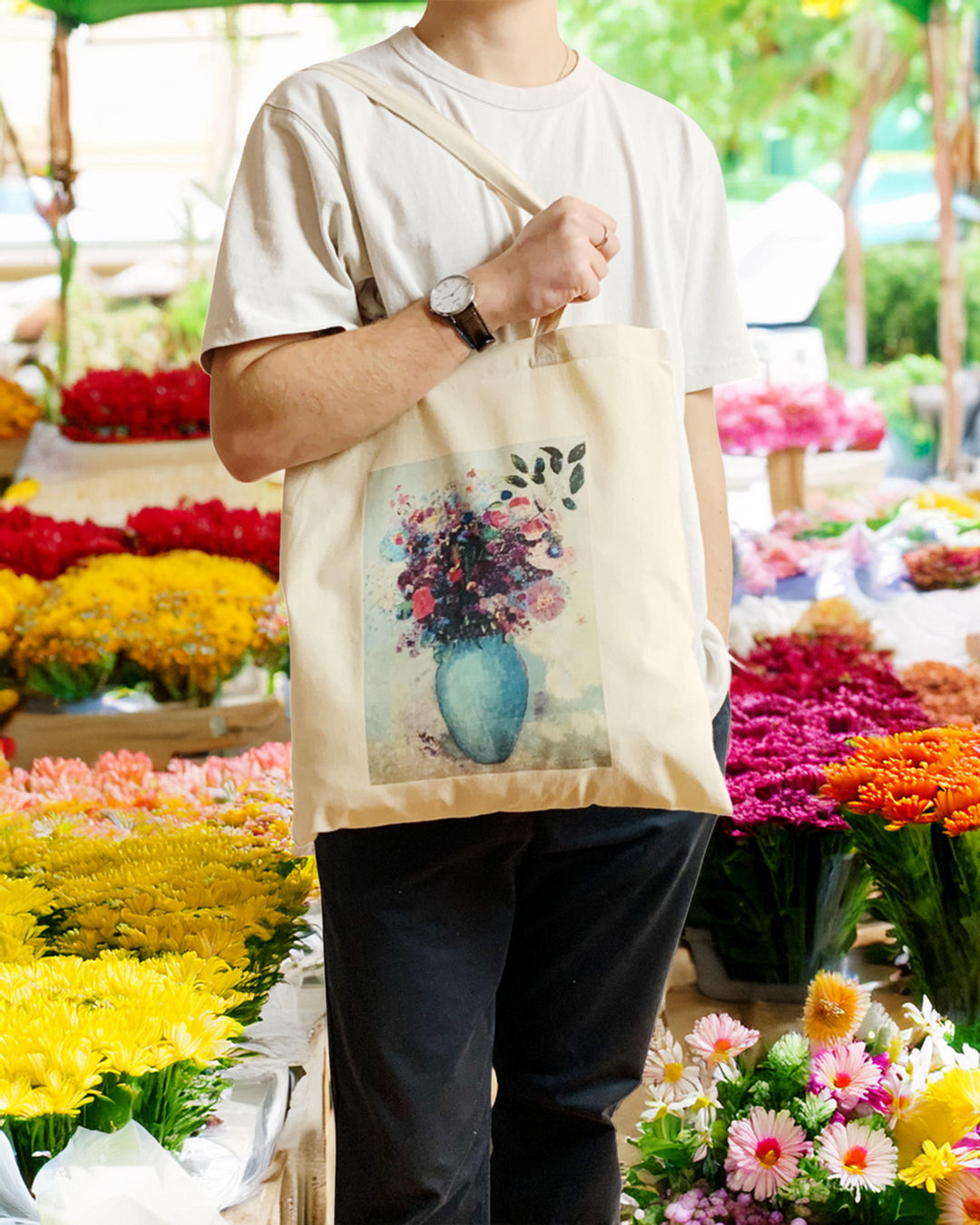 Person holding a tote bag with a floral design at a flower market.