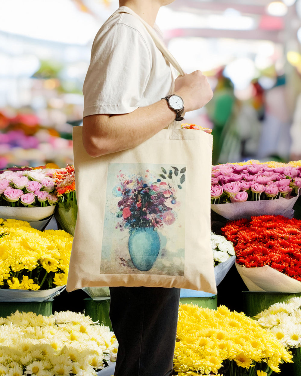 Person holding a tote bag with a floral design in a flower market.