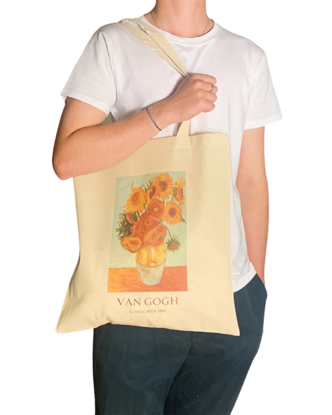 Person holding a tote bag with Van Gogh artwork featuring sunflowers.