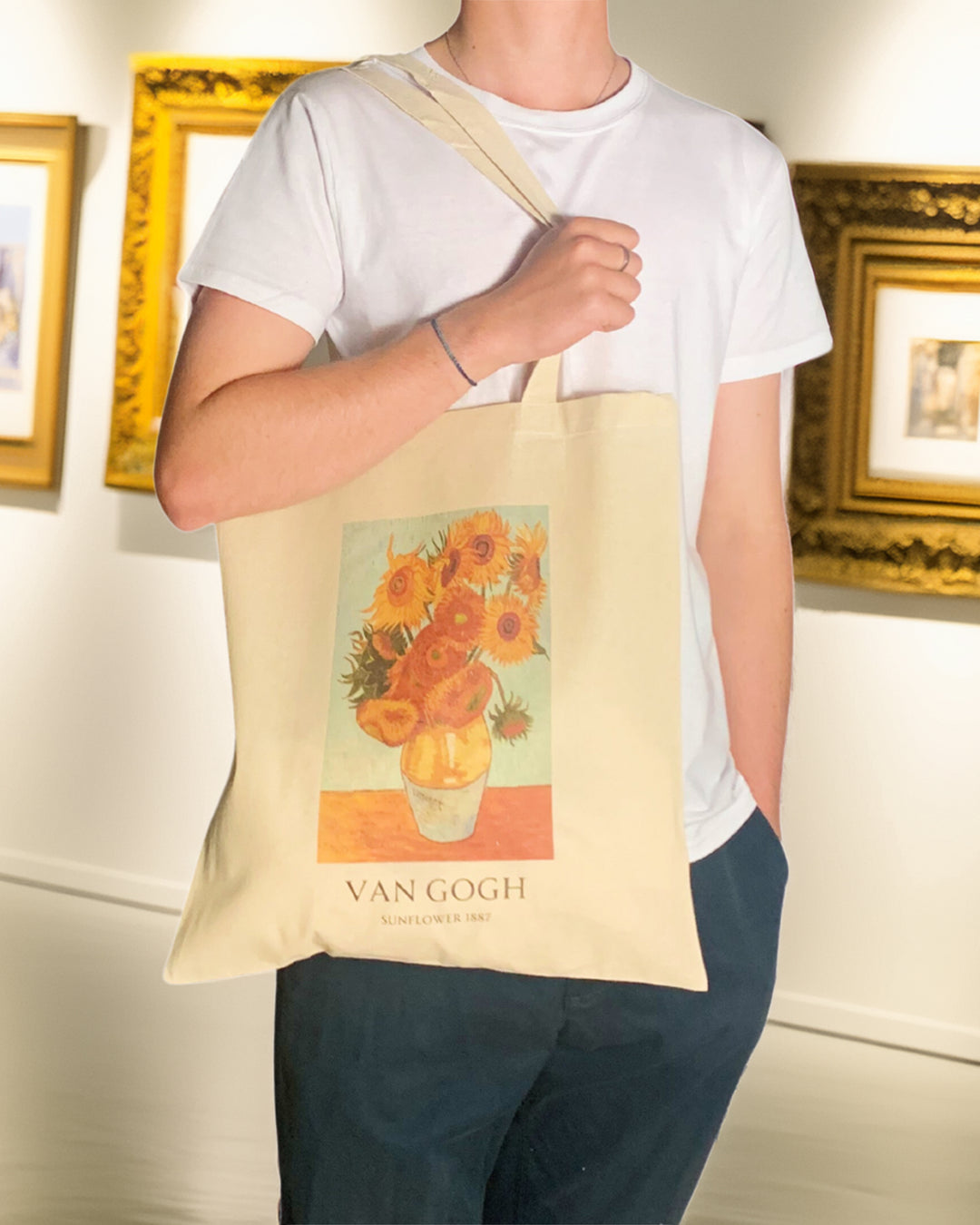 Person holding a tote bag with Van Gogh artwork in an art gallery setting